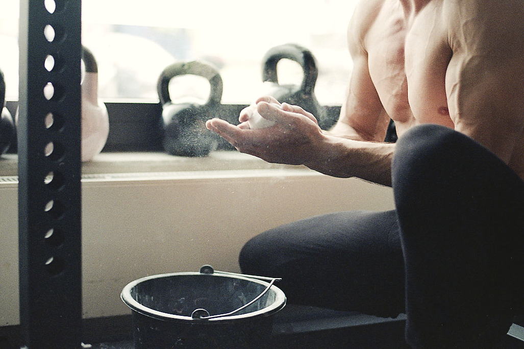 Hände mit Magnesia vor Kettlebells am Fenster